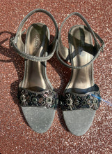 Load image into Gallery viewer, Silver glittery sandals with decorative straps on a concrete surface