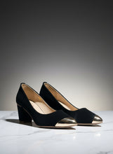Load image into Gallery viewer, Black high-heeled shoes with gold cap toecaps on a concrete surface