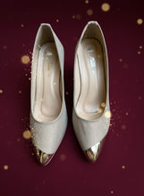 Load image into Gallery viewer, Pair of beige pointed-toe shoes with metallic gold tips on a gray concrete surface