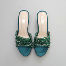Load image into Gallery viewer, Pair of teal sandals with green beaded embellishments on a gray surface