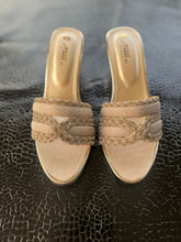Load image into Gallery viewer, Pair of gold sandals with decorative straps on a textured black surface