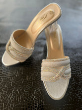 Load image into Gallery viewer, Pair of gold and silver high-heeled shoes on a textured black surface