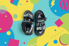 Load image into Gallery viewer, Pair of black children's sandals with brand logos on a gray surface
