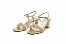 Load image into Gallery viewer, Gold high-heeled shoes with embellishments on a concrete floor