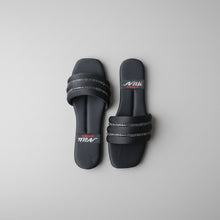 Load image into Gallery viewer, Black slides with a brand logo on a gray tiled floor