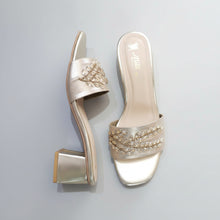 Load image into Gallery viewer, Pair of golden high-heeled shoes with embellishments on a gray marble surface