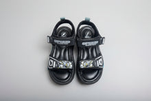 Load image into Gallery viewer, Pair of black sandals with colorful straps on a concrete surface