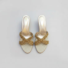 Load image into Gallery viewer, Pair of gold glittery shoes with decorative bows on a gray surface