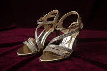 Load image into Gallery viewer, Gold and silver strappy high-heeled shoes on a dark surface