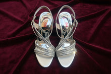 Load image into Gallery viewer, Silver strappy high-heeled shoes on a reflective surface