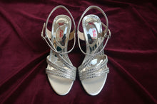 Load image into Gallery viewer, Silver high-heeled sandals with rhinestone straps on a reflective surface