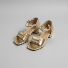 Load image into Gallery viewer, Gold high-heeled shoes with a strap on a gray surface