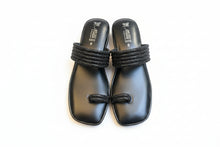 Load image into Gallery viewer, Pair of black sandals with woven straps on a beige surface