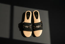 Load image into Gallery viewer, Black sandals with metallic buckle details on a concrete surface