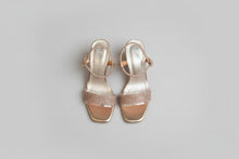 Load image into Gallery viewer, Pair of gold high-heeled sandals with rhinestone embellishments on a concrete surface.