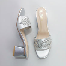 Load image into Gallery viewer, Silver high-heeled shoes with embellishments on a gray marble surface