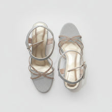 Load image into Gallery viewer, Pair of silver strappy sandals on a gray surface