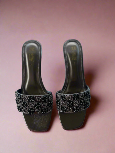 Pair of black high-heeled shoes with embellishments