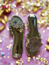 Load image into Gallery viewer, Gold sandals with floral embellishments on a white fabric background
