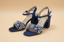 Load image into Gallery viewer, Blue high-heeled shoes with floral embellishments on a gray surface
