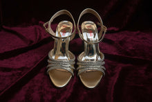 Load image into Gallery viewer, Pair of gold high-heeled sandals with rhinestone straps on a gray surface.
