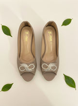 Load image into Gallery viewer, Pair of beige high-heeled shoes with decorative elements on a dark blue background
