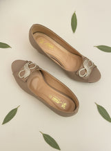 Load image into Gallery viewer, Pair of beige shoes with decorative elements on a dark blue background
