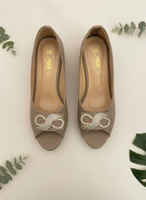 Load image into Gallery viewer, Beige high heels with decorative heart and bow on a dark blue background
