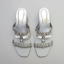 Load image into Gallery viewer, Silver glittery sandals with rhinestone embellishments on a gray surface
