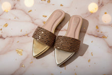 Load image into Gallery viewer, Gold embellished pointed-toe slides on a marble surface with gold confetti.
