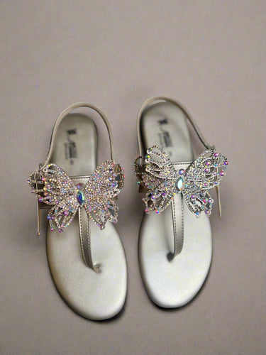 Pair of sandals with butterfly embellishments on a gray surface