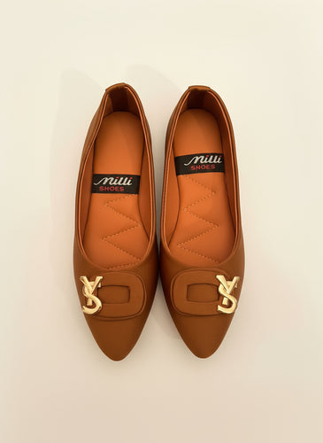 Pair of orange shoes with gold accents on a dark surface