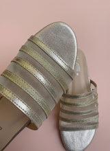 Load image into Gallery viewer, Close-up of a sandal with metallic straps on a textured surface
