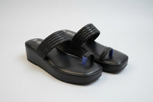 Load image into Gallery viewer, Pair of black sandals with decorative straps on a beige surface
