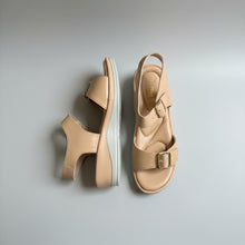 Load image into Gallery viewer, Pair of beige sandals with a buckle on a gray surface
