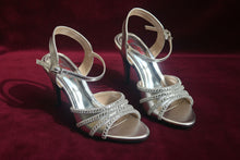 Load image into Gallery viewer, Pair of silver high-heeled shoes on a concrete surface
