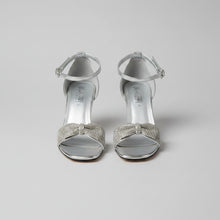 Load image into Gallery viewer, Pair of silver high-heeled sandals with rhinestone embellishments on a textured surface.
