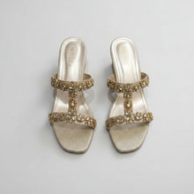 Load image into Gallery viewer, Pair of glittery high-heeled shoes with gold embellishments on a gray surface
