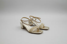 Load image into Gallery viewer, Pair of gold sandals with glittery straps on a concrete floor
