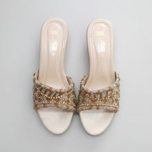 Load image into Gallery viewer, Pair of white sandals with gold embellishments on a gray surface
