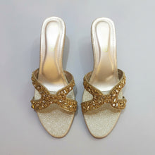 Load image into Gallery viewer, Pair of gold glittery shoes with decorative straps on a gray surface
