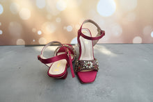 Load image into Gallery viewer, Pair of red high-heeled sandals with embellishments on a gray surface
