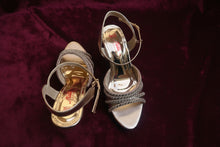 Load image into Gallery viewer, Pair of gold high-heeled sandals on a gray surface

