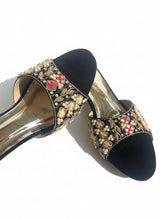 Load image into Gallery viewer, Decorative black high-heeled shoe with gold embellishments on a reflective surface
