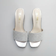 Load image into Gallery viewer, Pair of silver glittery high-heeled shoes on a gray marble surface
