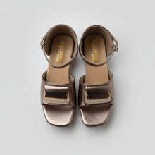 Load image into Gallery viewer, Pair of metallic sandals on a textured gray surface
