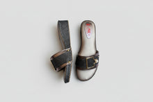 Load image into Gallery viewer, Pair of sandals with glittery strap and gold buckle on a gray surface with pink flowers.
