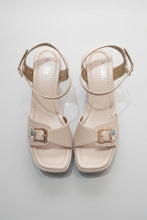 Load image into Gallery viewer, Pair of beige high-heeled sandals with buckles on a gray surface

