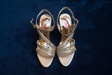 Load image into Gallery viewer, Pair of gold and silver strappy high-heeled sandals on a gray surface
