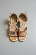 Load image into Gallery viewer, Pair of bronze sandals with rhinestone embellishments on a gray surface
